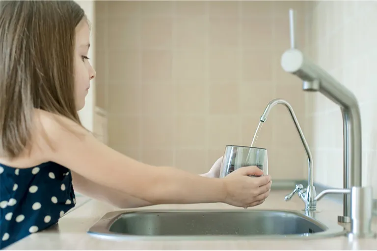 Child filling a glass of clean, filtered water